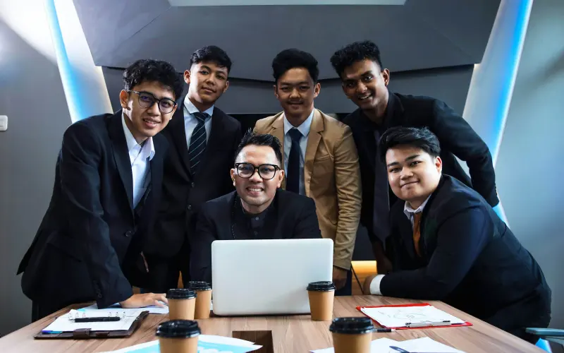 Team of professionals gathered around a laptop in a meeting room