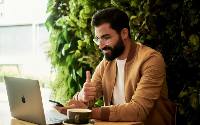 Entrepreneur working on a laptop with plants behind him